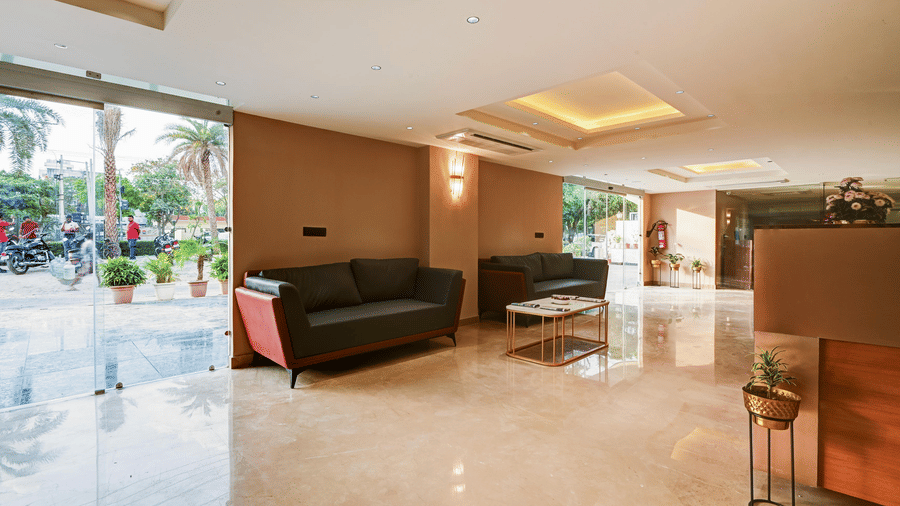 The lobby area of Hotel 91 Privé, Gurugram, with a waiting area and a glass door at the entrance beside it.