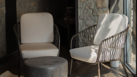 A seating area at Kavya Himalayas, Nagarkot featuring two wooden furnished chairs and a center table.