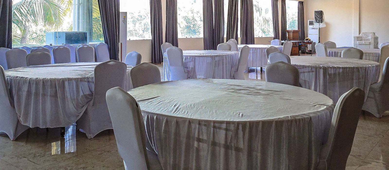 Indoor banquet hall with round tables draped in white cloth for events at The Verda de Miranda Resort.