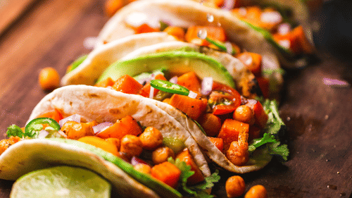 tacos lined up with lemon being squeezed on top of them