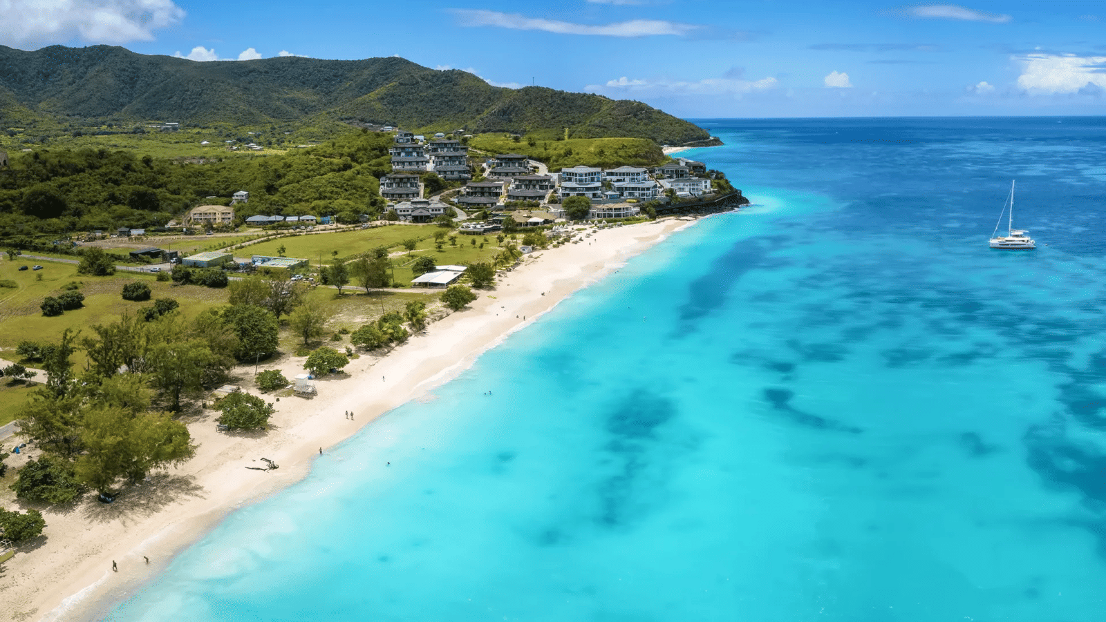 aerial shot of the turquoise blue waters of Ffryes Beach reaching the golden sands of Antigua island | Tamarind Hills Resort and Villas - Antigua