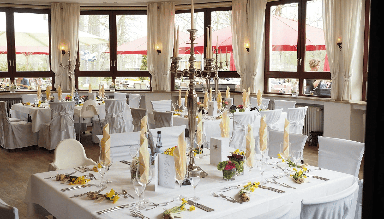 Image of a banquet hall with cutleries and napkins placed in the glasses. 