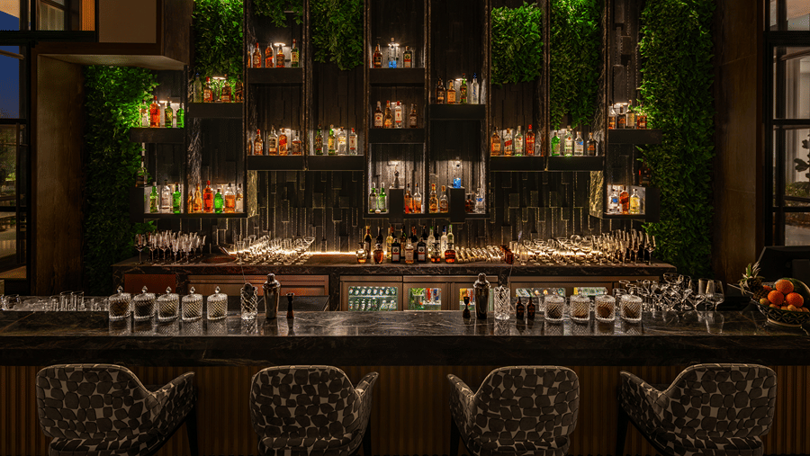 Eden bar with a well stocked shelf and hanging greenery above the counter at The Residency Signature Madurai.