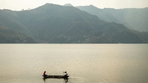 An image of a boat sailing on a lake with beautiful mountain ranges in the background