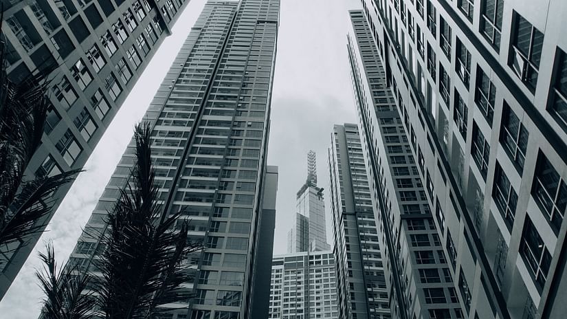 Massive buildings in view from the bottom with the image in greyscale.