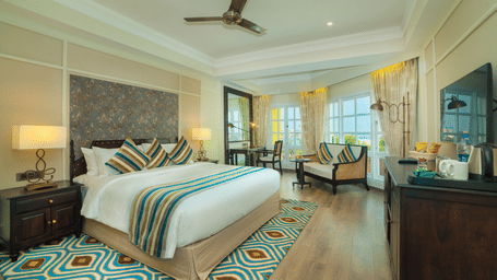 Spacious room with a large bed neatly arranged with cushions and blankets, surrounded by wooden furniture at Fragrant Nature Cochin