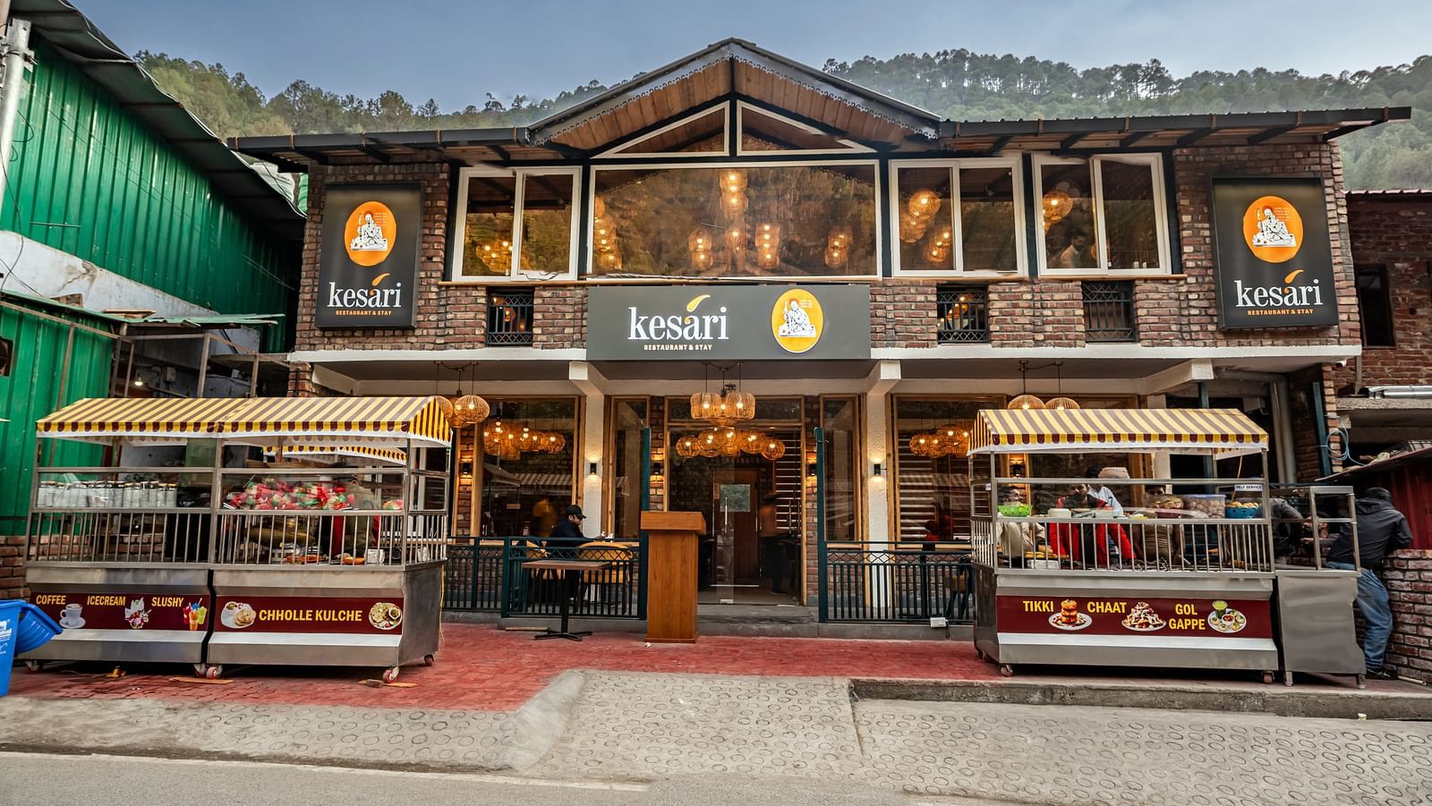 Facade of the Kesari Restaurant with two stalls selling various Indian fast foods with a clear blue sky in the background.