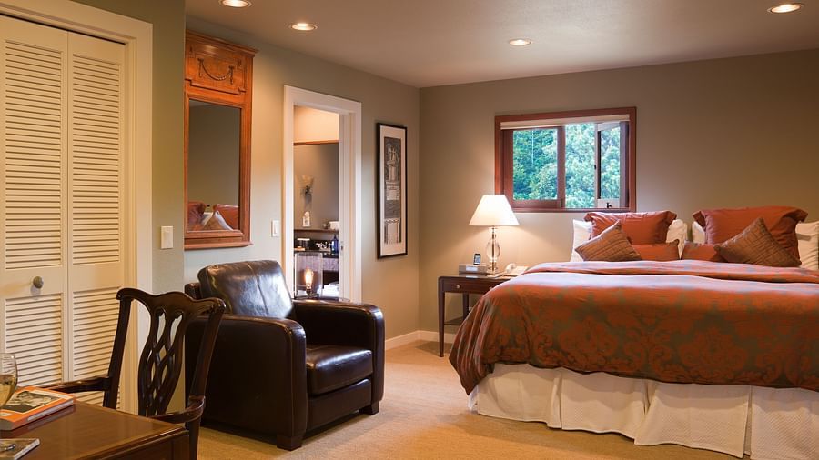 A view of Meadowview suite featuring a leather couch, a plush bed, and a night stand with lamp - Brewery Gulch Inn & Spa