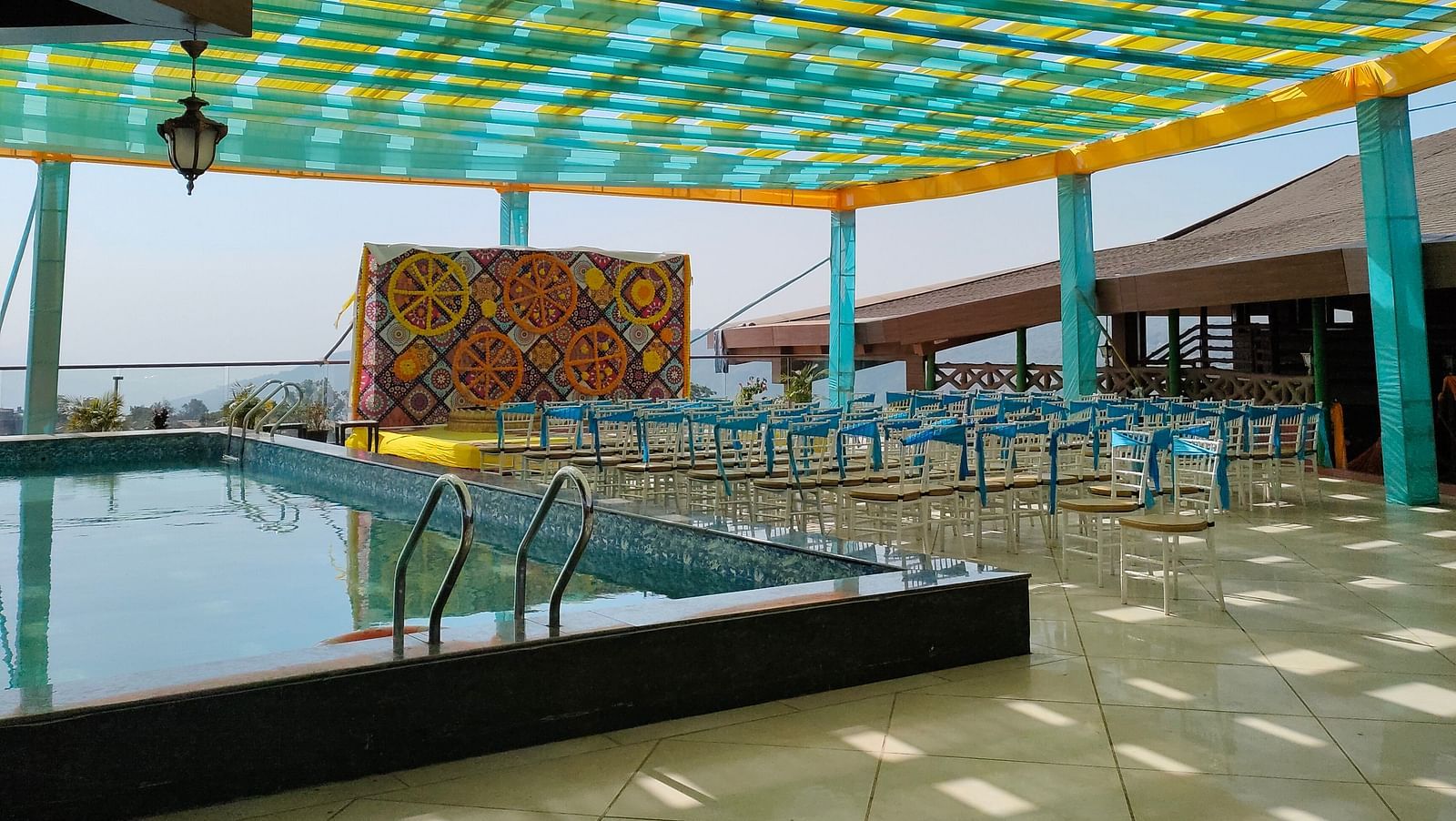 Seating arrangement made near swimming pool at The Grand Legacy Resort & Spa featuring several chairs and a stage decorated with large fabric pieces and flowers