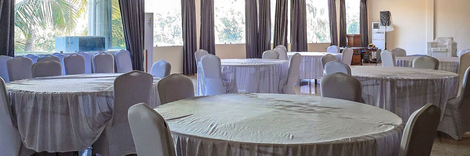 Indoor banquet hall with round tables draped in white cloth for events at The Verda de Miranda Resort.