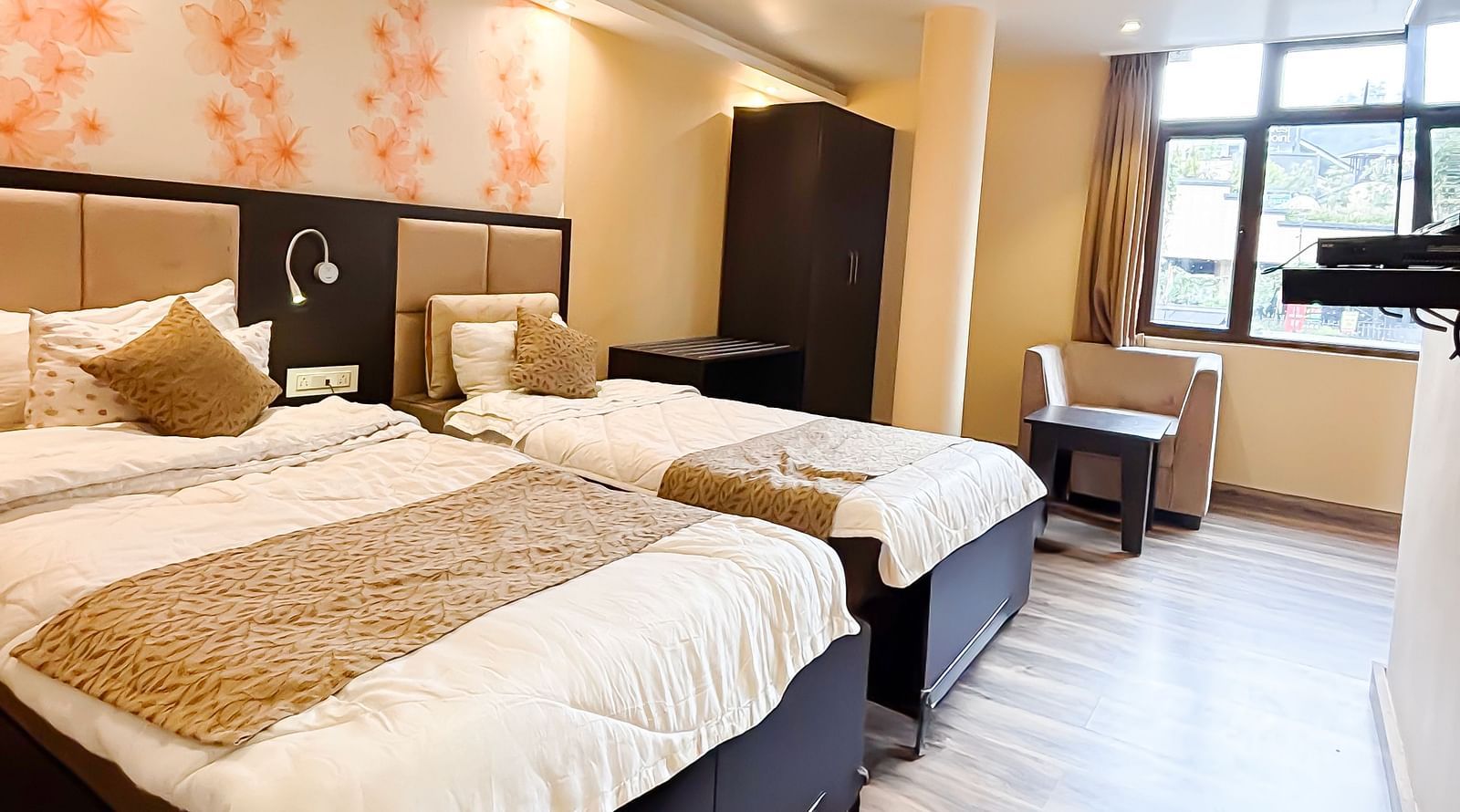A bedroom with two queen beds and a floral wallpaper behind the beds at Avianna Hungry Jack, Gangtok.