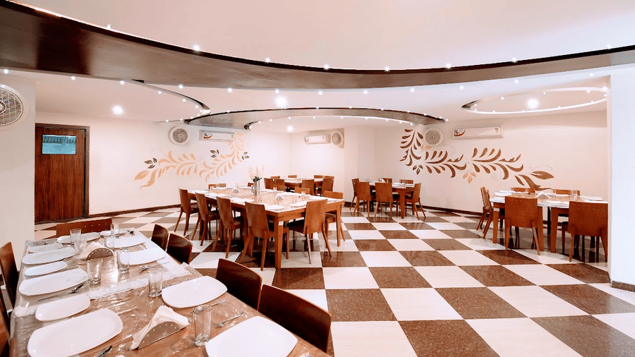 Arranged dining seating setup showing multiple wooden dining tables under modern ambient ceiling lights.