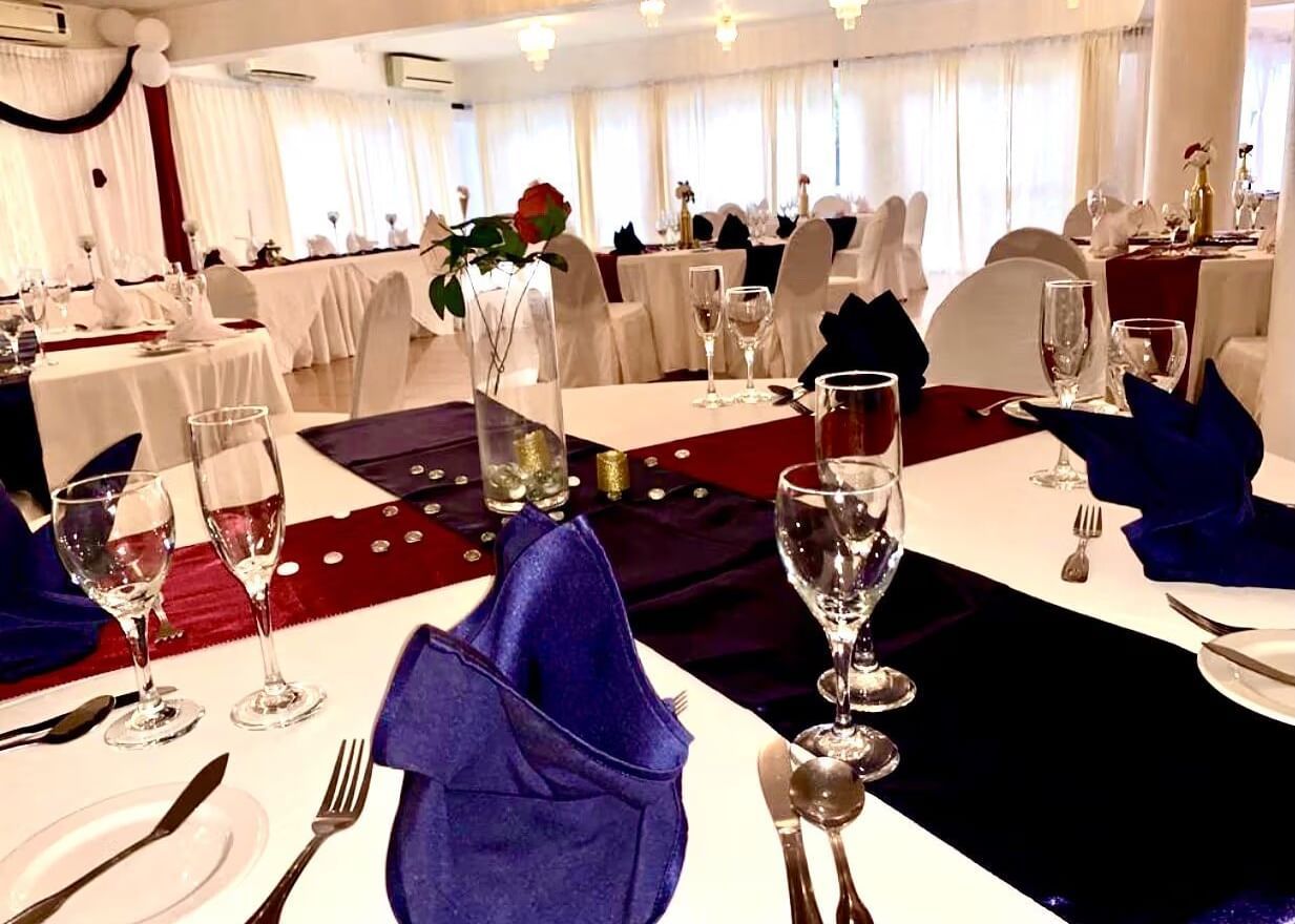 A formal dining table is set with blue and red napkins, glasses, and place settings | Luxor | Altamont Court, Jamaica