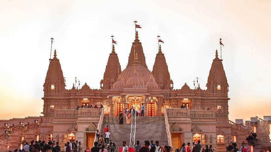 A grand Hindu temple with multiple spires, illuminated at dusk with many visitors ascending the stairs