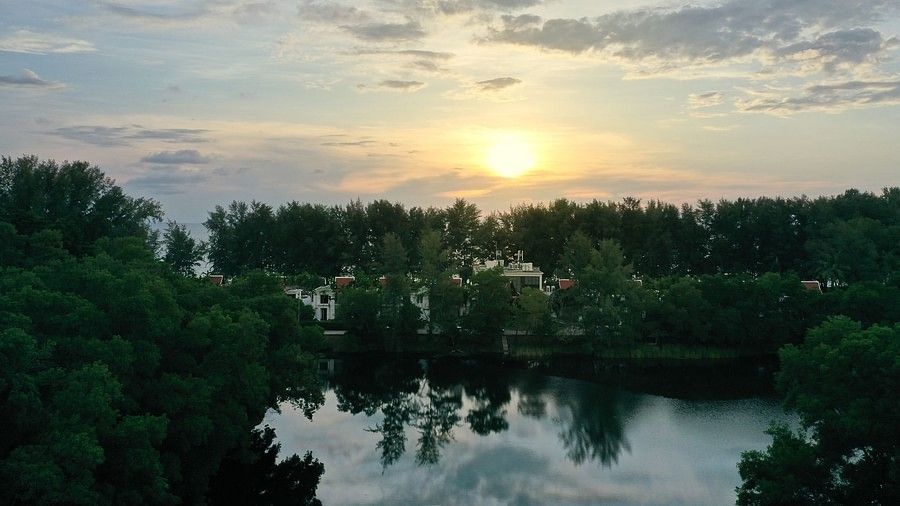 a beautiful sunset amidst the lush forests in phuket - maikhao dream villa resort and spa