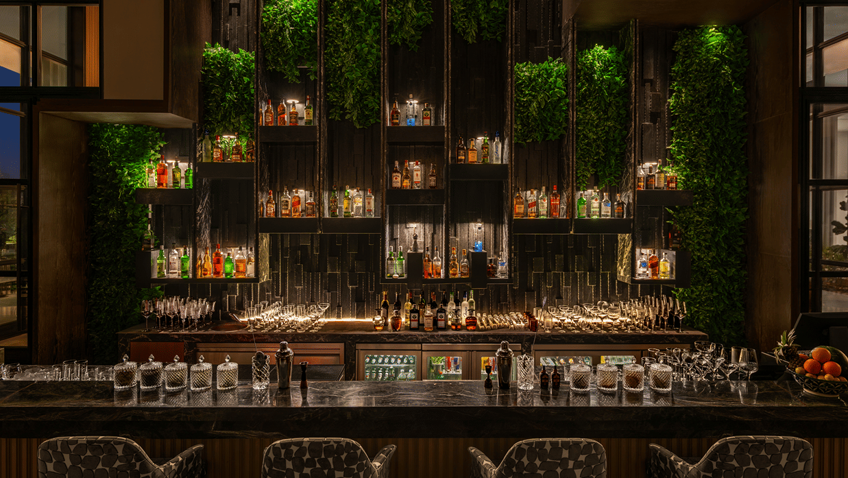 Eden bar with a well stocked shelf and hanging greenery above the counter at The Residency Signature Madurai.