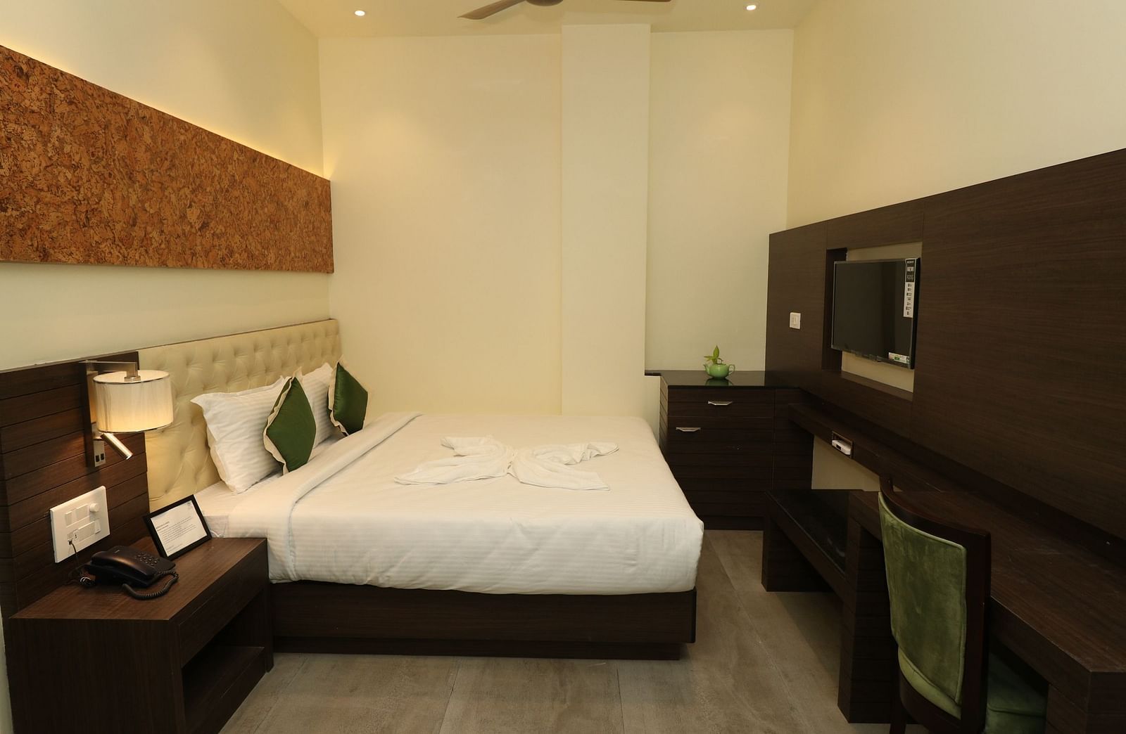 A hotel bedroom with a large bed, a wooden coffee table, and an armchair, showcasing a well-lit and comfortable space - Sea Hills Hotels, Sri Vijaya Puram (Port Blair)