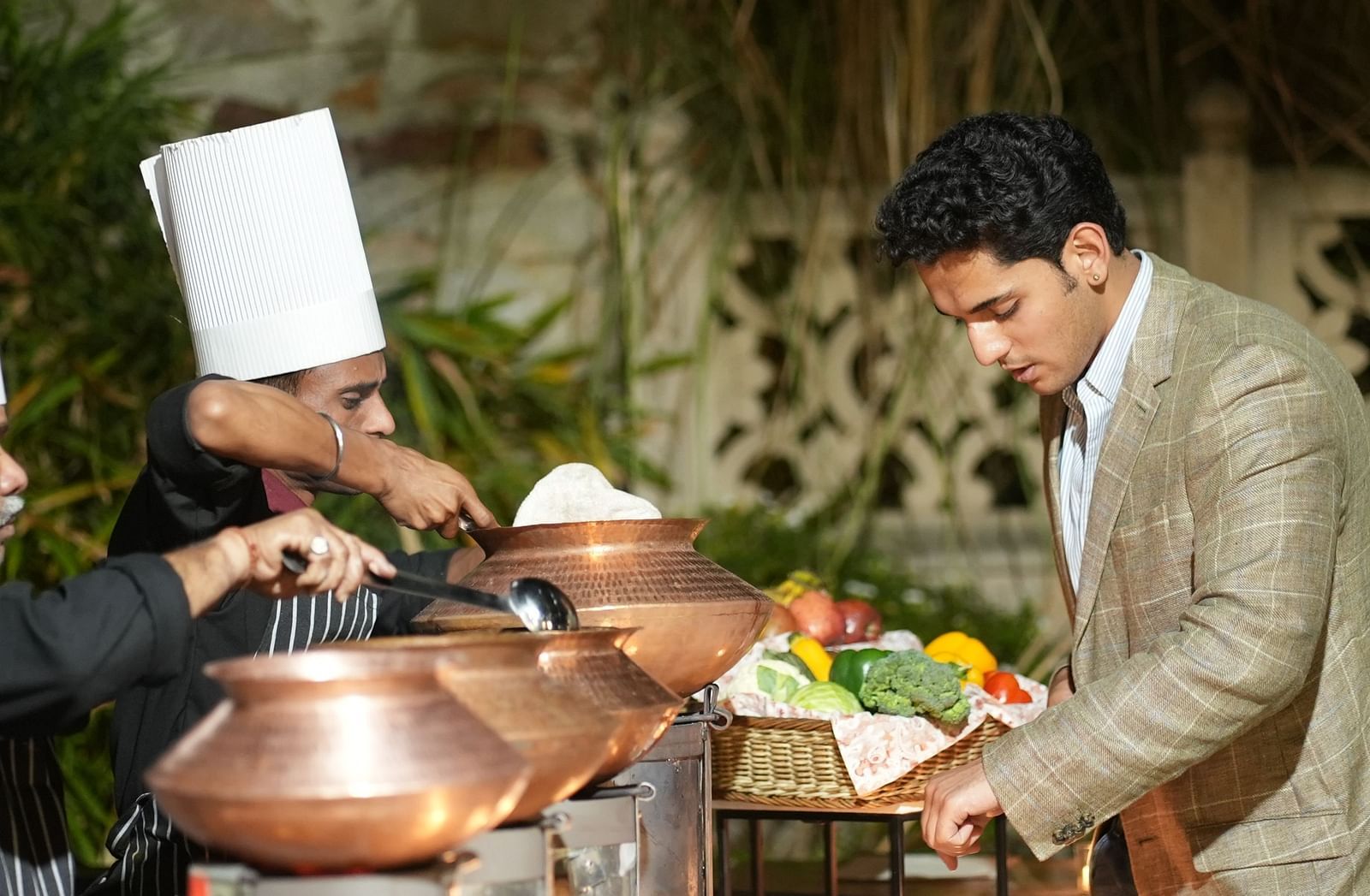 A chef and a guest discuss the menu beside a buffet spread in traditional copper pots - Khas Bagh, Jaipur.