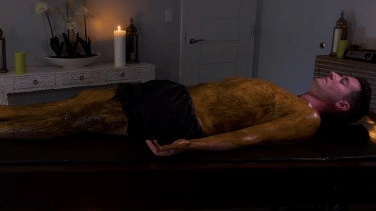A man lying on a massage bed indoor with a candle lit in the background on a side table at YO1 Longevity & Health Resorts