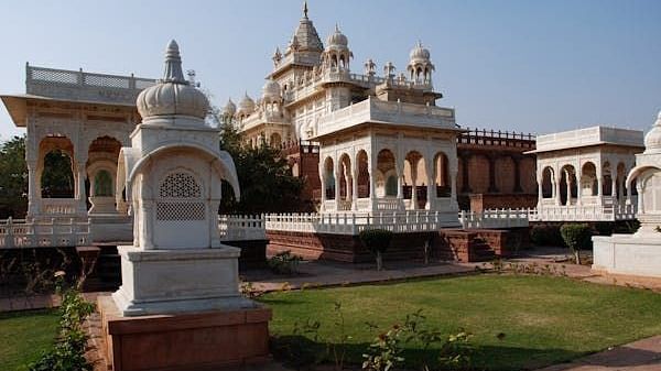 A facade image of a white and brown palace with a lawn in front of it