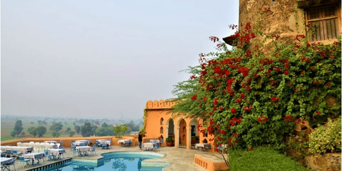  a fort with plants growing close to the walls and a pool nearby