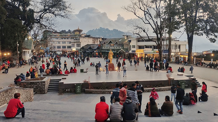 A busy open square at Chowrasta Mall Road in Darjeeling with people sitting and gathering.