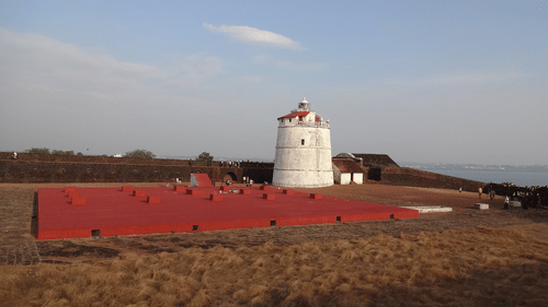 Lighthouse at Fort Aguada surrounded by sand and clear skies