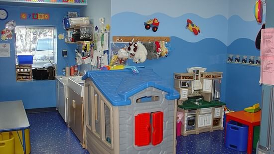 A brightly coloured children's playroom features a playhouse, toy kitchen, tables, chairs, and wall decorations with a playful theme at Uday Samudra Leisure Beach Hotel, Kovalam