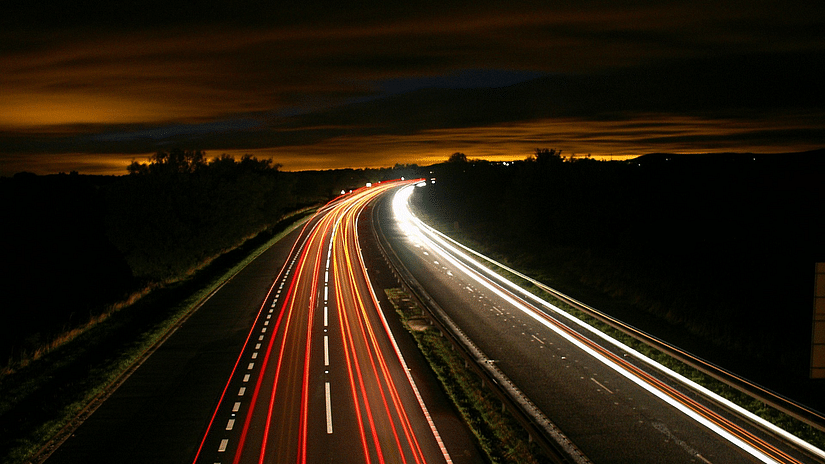 A long highway with traffic lights at dusk