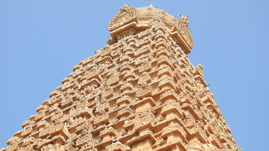 A view from below of a temple with stone carvings of deities on the gopurams, signifying Marudhamalai Temple, one of the Coimbatore places to visit.