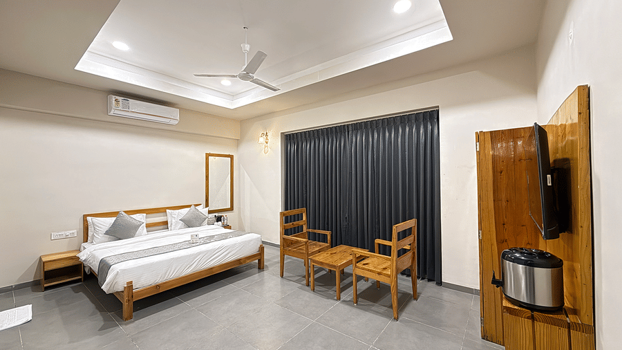 A comprehensive view of a guest suite showing the bed, seating area, and wall-mounted television console - Daksh The Nirvana Retreat, Pavagadh