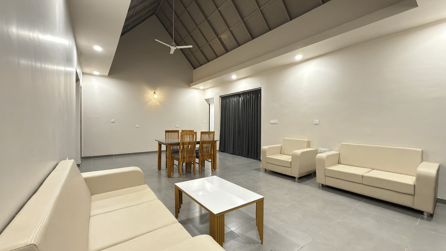 An expansive living room view showing comfortable cream sofas and a dining area under a vaulted ceiling - Daksh The Nirvana Retreat, Pavagadh