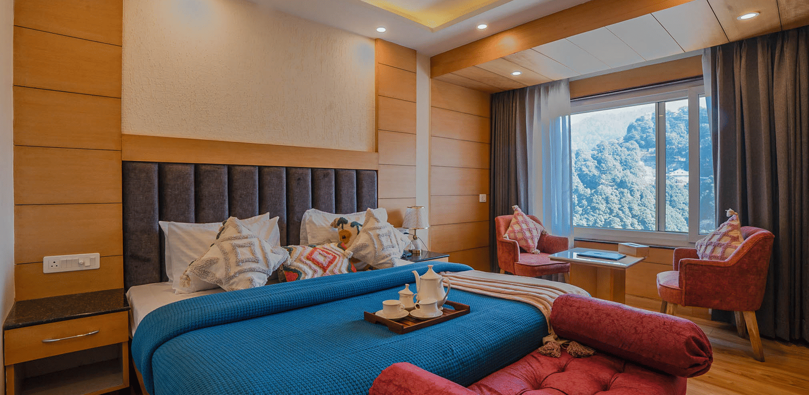 A bedroom with a bed, chairs, and large window at Perfectstayz Premium at Mall Road Hotel Super, Mussoorie.