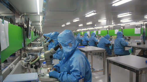 people in ppe suits working on chipsets inside a clean room
