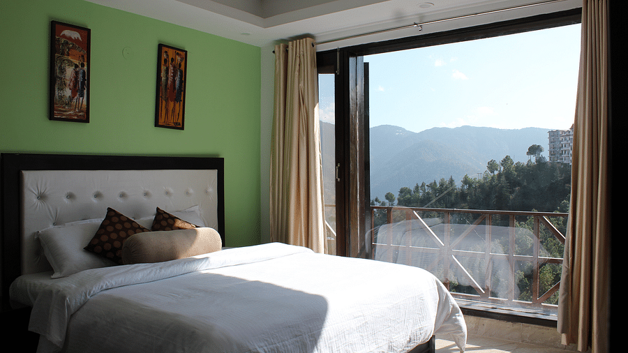 A side view of the king size bed beside a huge glass window - Silverpine Apartments & Homestay, Mehli