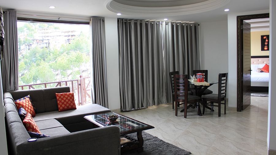 A full view of the attached living room decked with a sofa set, teepoy, and a dining table - Silverpine Apartments & Homestay, Mehli