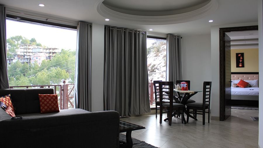 A full view of the living area with huge glass windows whose curtains are drawn wide open - Silverpine Apartments & Homestay, Mehli