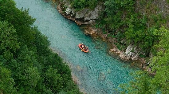 A top view of a valley featuring a winding river and a riverboat gliding along the water, surrounded by lush greenery and natural landscapes