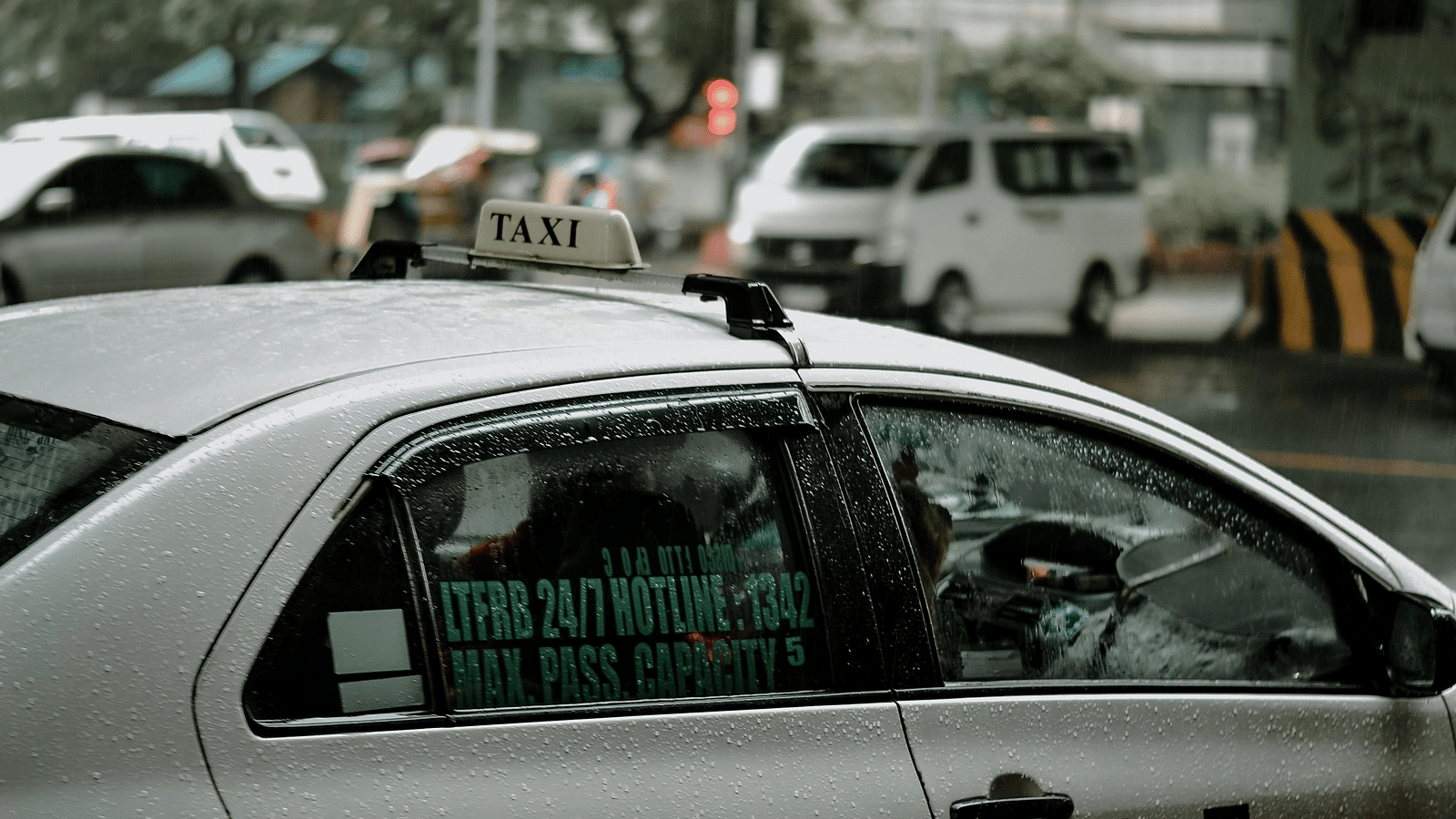 image of a white coloured taxi with windows closed in a rainy day 
