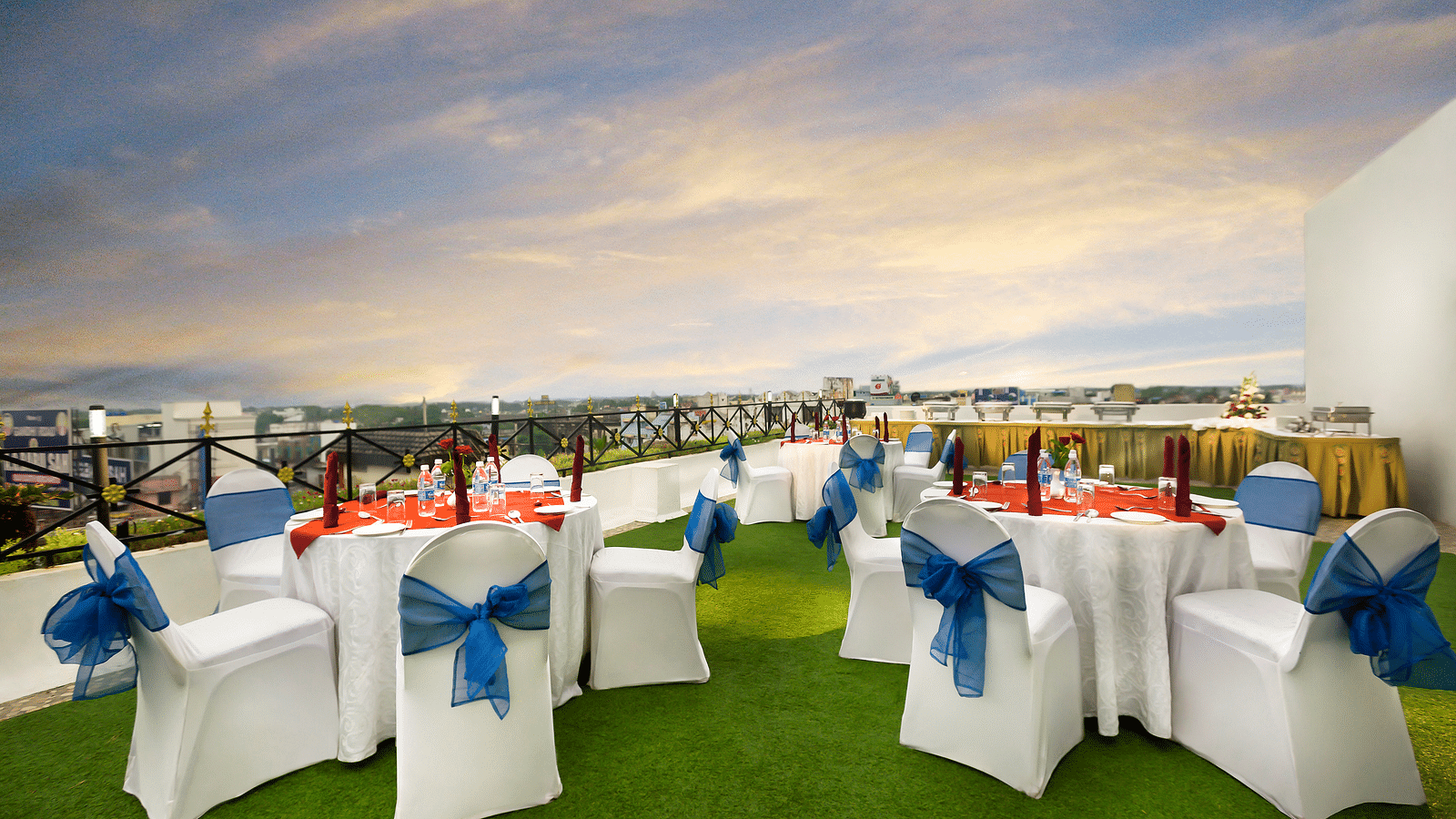 A banquet hall with white chairs laced with blue ribbons pointing towards the stage at Regency Kanchipuram by GRT Hotels.