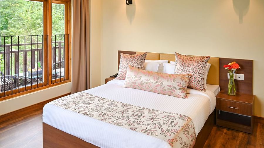 the premier room with balcony at Yashshree Karbari Resort & Spa, Yangang featuring a queen size bed besides a huge window