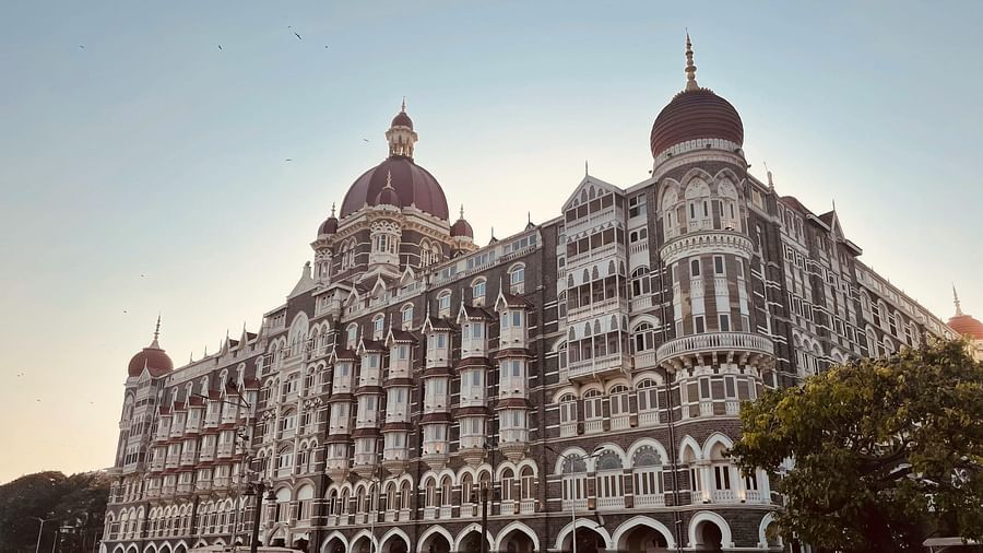An image of Taj Hotel in Mumbai and in front of it there are bird sitting on the ground