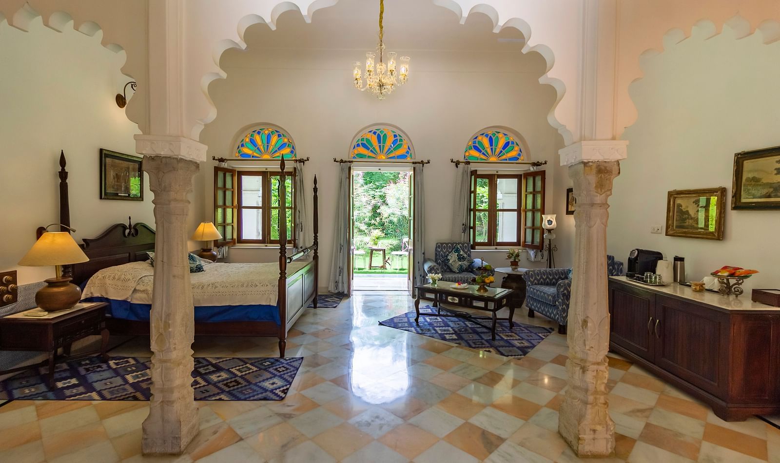 image of the Deluxe suite at Dev Shree, deogarh through the arched pillars featuring a double bed