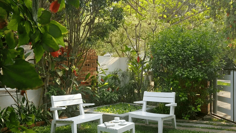 White garden seating set on a green lawn surrounded by trees and plants at Amanvana Spa Resort in Coorg.