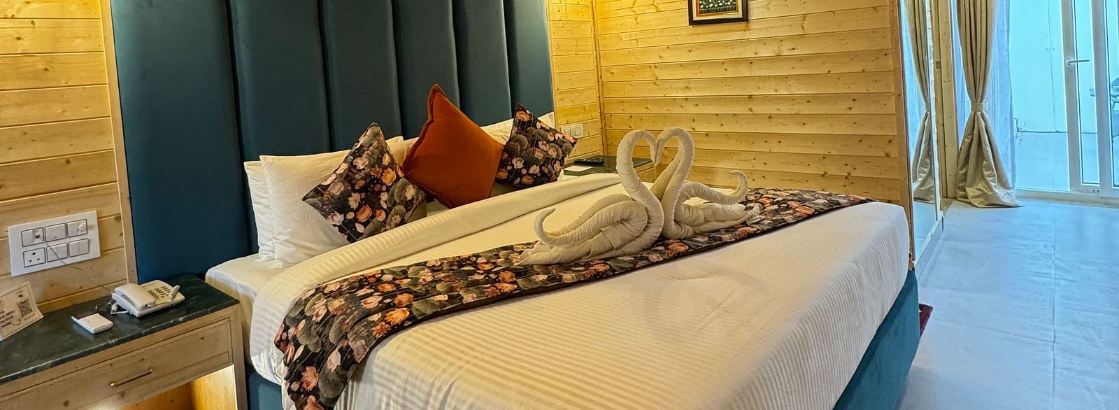 An interior shot of a hotel room with wooden paneled walls. The room has a bed with a white comforter and a decorative runner - Bamboo Saa Mulberry Resort, Pushkar