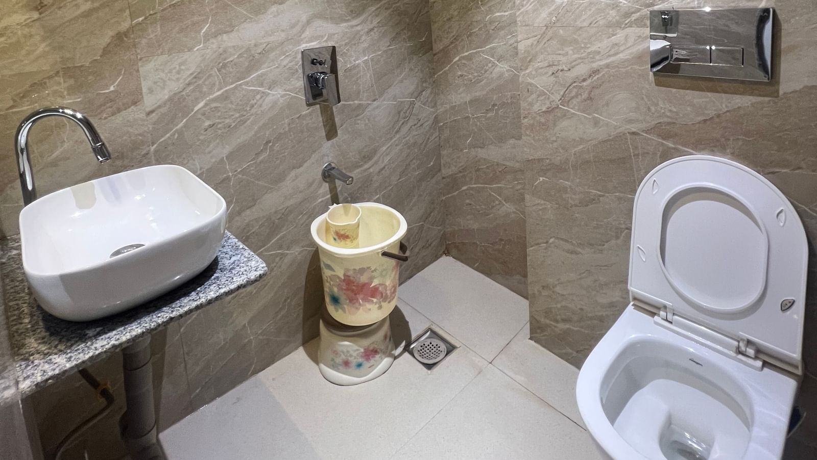 Bathroom of Daksh Comfort Room furnished with a western commode, a sink, and other bathroom fittings | Daksh The Valley Resort, Saputara