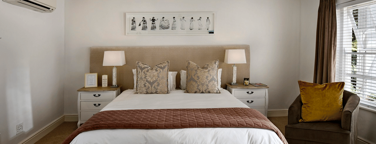 A king size bed with a ceiling fan hanging over it in a bedroom. 