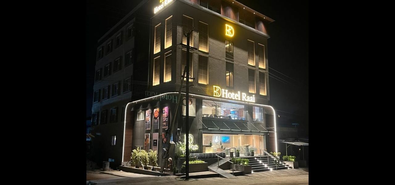 Facade of Hotel Raai at night featuring multiple storeys,  and each room is illuminated with lights. The brand name is illuminated as well.
