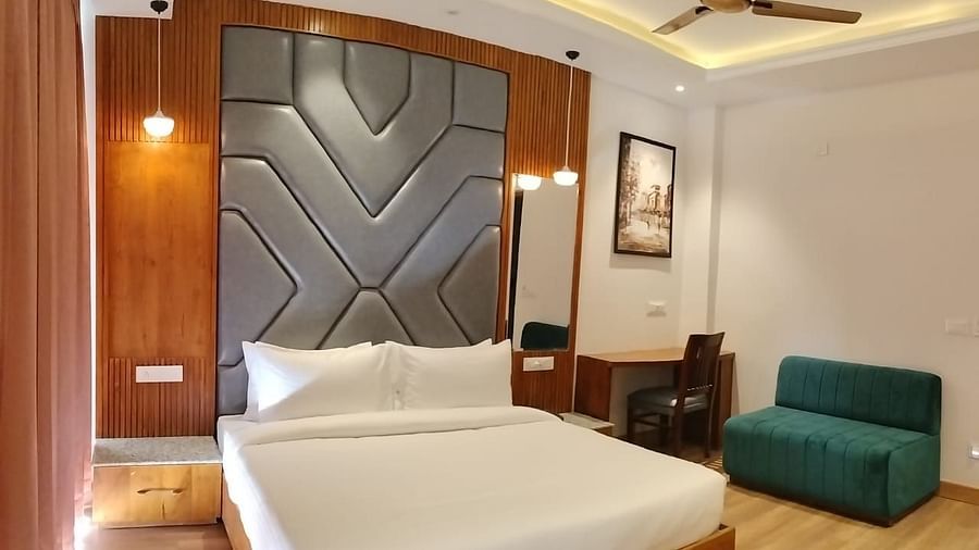 A large bed placed next to a sofa in Premium Room With Balcony at DLS Ark Holiday Inn, Banikhet.