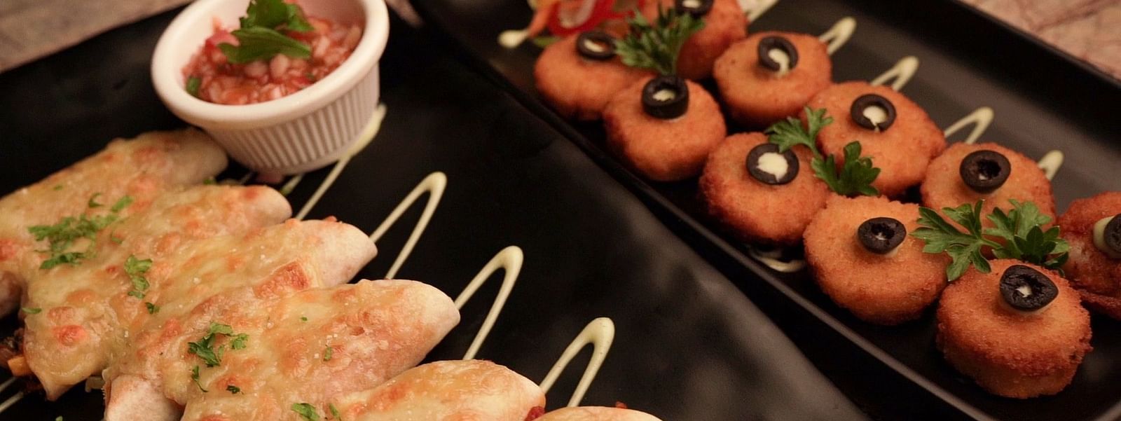 An image of image of cheese balls and fritters served on a trays with dips - Pai Group of Hotels
